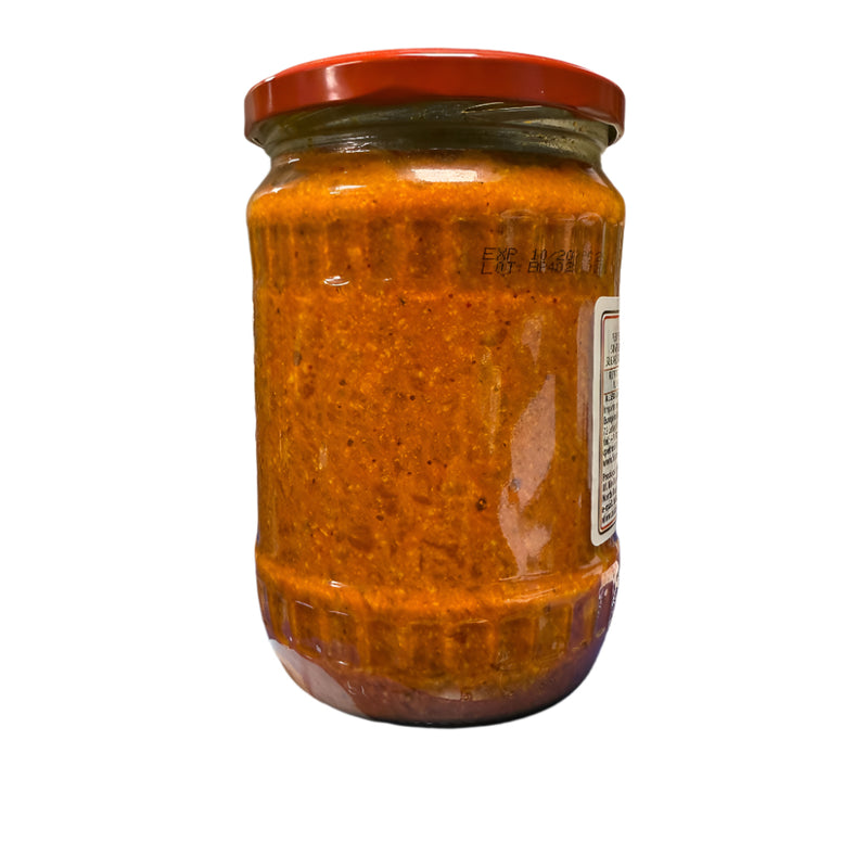 Jar of red sauce on a blue surface with a tiled wall in the background