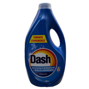 A blue bottle of Dash laundry cleaner placed on a metal counter inside a store or warehouse setting, with cardboard boxes and other products visible in the background.