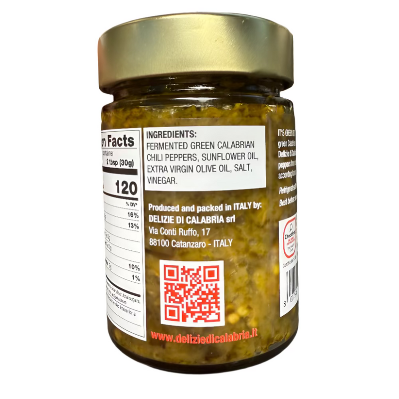 Jar of pickled green peppers with a gold lid, held by a hand on a dark surface.