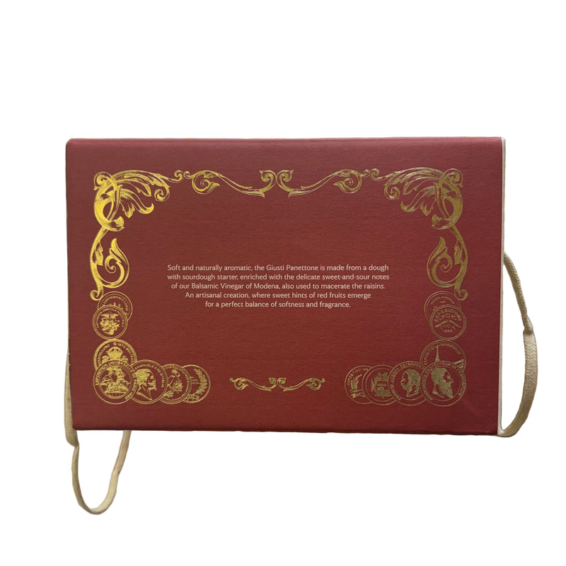 Decorative box with gold text and designs held in a hand, blurred store interior in the background