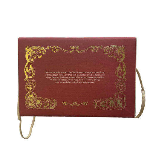 Decorative box with gold text and designs held in a hand, blurred store interior in the background