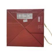 Close-up of a red box with text and a barcode, held in front of a store shelf.