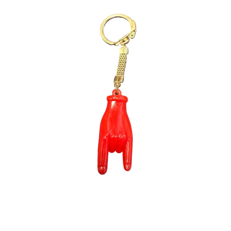 Red keychain shaped like a robot on a textured black surface