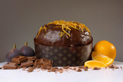 Chocolate cake with orange zest, surrounded by chocolate bars and oranges on a gray background