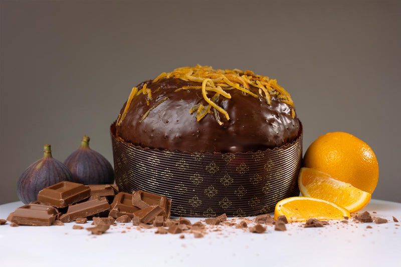 Chocolate cake with orange zest, surrounded by chocolate bars and oranges on a gray background