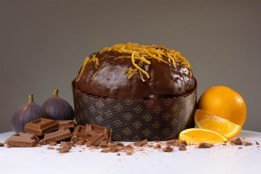 Chocolate cake with orange zest, surrounded by chocolate bars and oranges on a gray background