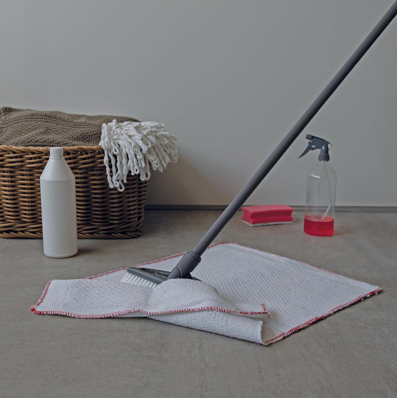 Cleaning mop with cloth head on a floor, next to cleaning supplies.