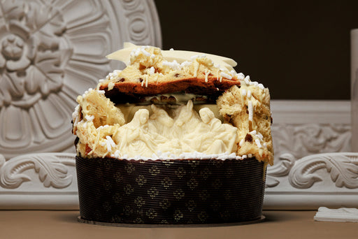 Close-up of a layered dessert with white cream and chocolate base, set against a decorative white background.