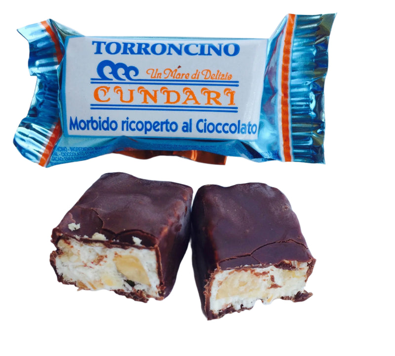 Packaging and pieces of Cundari soft nougat covered with dark chocolate, with visible nuts and pistachio inside.