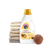 A bottle of Chanteclair detergent for wool and cashmere, alongside a stack of folded wool garments and a piece of wool fabric with a ball of yarn.